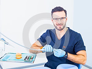 Healthcare, profession, stomatology and medicine concept - smiling male dentist over medical office background