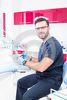 Healthcare, profession, stomatology and medicine concept - smiling male dentist over medical office background