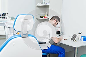 Healthcare, profession, stomatology and medicine concept - smiling male young dentist over medical office background