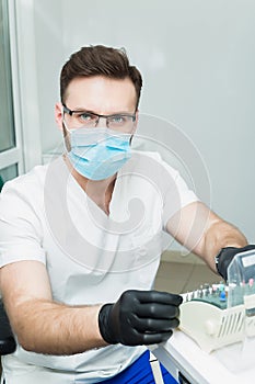 Healthcare, profession, stomatology and medicine concept - smiling male young dentist over medical office background