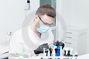 Healthcare, profession, stomatology and medicine concept - smiling male young dentist over medical office background