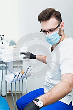 Healthcare, profession, stomatology and medicine concept - smiling male young dentist over medical office background