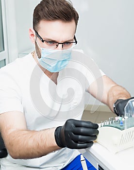 Healthcare, profession, stomatology and medicine concept - smiling male young dentist over medical office background