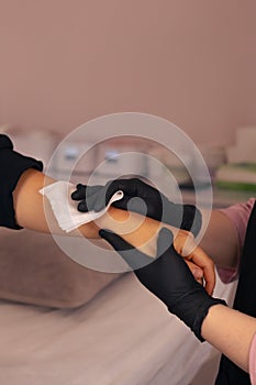 A professional applying a bandage on a clients arm in a clean treatment room photo