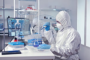 Healthcare scientist taking sample from test tube using automatic pipette