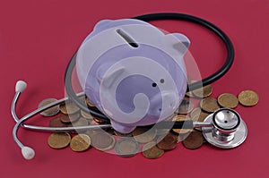 Healthcare spending concept with piggy bank, stethoscope and coins on red background