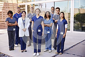 Healthcare team with ID badges stand outdoors, full length