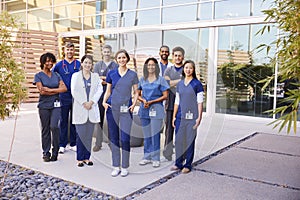 Healthcare team with ID badges stand outdoors, full length