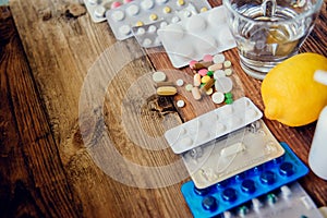 healthcare, traditional medicine and flu concept - drugs, thermometer, honey and cup of tea on wooden table