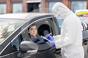 Healthcare worker with clipboard and woman in car