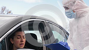 Healthcare worker with clipboard and woman in car