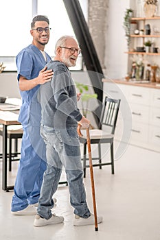 Healthcare worker helping a man to walk with a cane