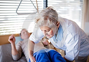 A healthcare worker helping paralysed senior patient in hospital. photo