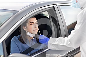 Healthcare worker making coronavirus test at car