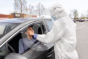 Healthcare worker making coronavirus test at car