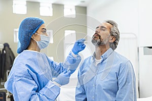 Healthcare worker with protective equipment performs coronavirus swab on elderly man. Nose swab for Covid-19