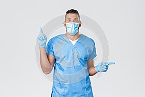 Healthcare workers, covid-19, coronavirus and virus concept. Excited male doctor, nurse in blue scrubs and medical mask