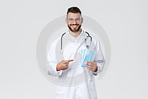 Healthcare workers, medical insurance, pandemic and covid-19 concept. Cheerful, smiling handsome doctor recommend using