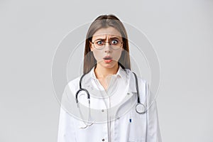 Healthcare workers, medicine, insurance and covid-19 pandemic concept. Shocked nervous female doctor in white scrubs and