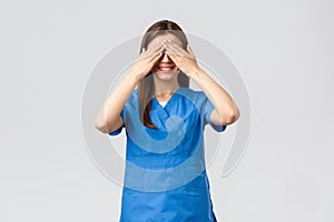 Healthcare workers, prevent virus, insurance and medicine concept. Young optimistic female nurse, doctor in scrubs, shut