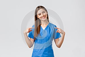Healthcare workers, prevent virus and medicine concept. Cheerful, smiling pretty doctor, female nurse in blue scrubs