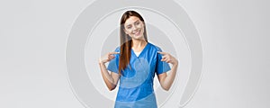 Healthcare workers, prevent virus and medicine concept. Cheerful, smiling pretty doctor, female nurse in blue scrubs