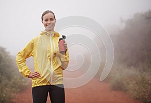 Healthiness is happiness. A young female runner training outdoors holding a water bottle.