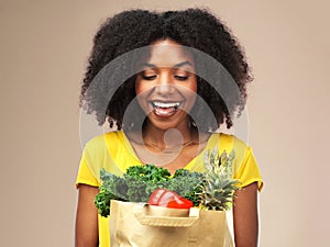 Healthiness is next to happiness. Studio shot of an attractive young woman holding a bag full of vegetables against a