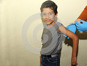 Healthy 7-year-old poor indigenous Latino boy receiving a vaccine against influenza and covid-19