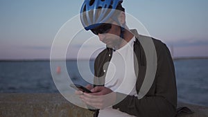 Healthy, active lifestyle and cycling travel. Caucasian man rode bicycle to sea and stopped to plot route on smartphone