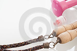 Healthy and active lifestyles Concept, bottle of water, jump rope and dumbbells on white glass table