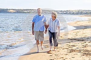 Healthy active senior couple holding hands, embracing each other and walking on beach