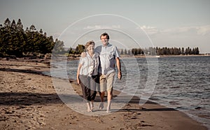 Healthy active senior couple holding hands, embracing each other and walking on beach