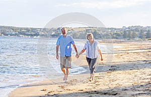 Healthy active senior couple holding hands, embracing each other and walking on beach