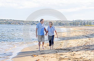 Healthy active senior couple holding hands, embracing each other and walking on beach