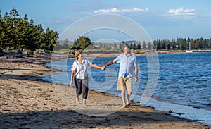 Healthy active senior couple holding hands, embracing each other and walking on beach