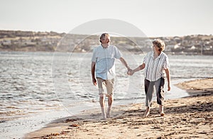 Healthy active senior couple holding hands, embracing each other and walking on beach
