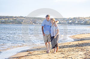 Healthy active senior couple holding hands, embracing each other and walking on beach