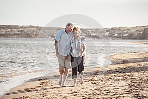 Healthy active senior couple holding hands, embracing each other and walking on beach