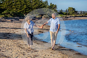 Healthy active senior couple holding hands, embracing each other and walking on beach