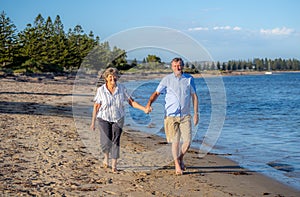 Healthy active senior couple holding hands, embracing each other and walking on beach