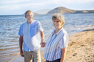 Healthy active senior couple holding hands, embracing each other and walking on beach