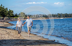 Healthy active senior couple holding hands, embracing each other and walking on beach