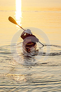 Healthy, active senior man sea kayaking at sunrise or sunset. Outdoor adventure water sports enjoying secure, independent