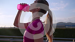 healthy active woman is running in early morning in city and drinking water