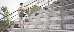 Healthy adult Asian female running up on concrete stairs of the city stadium