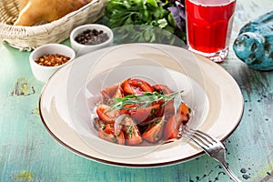 Healthy appetizer fresh tomato salad in white bowl with red onion and estragon on blue wooden table