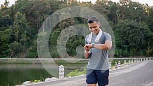 A healthy Asian man in sportswear is his calories burning on his smartwatch while running outdoors