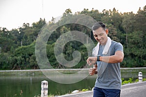 A healthy Asian man in sportswear is his calories burning on his smartwatch while running outdoors