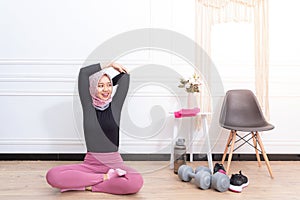 Healthy asian muslim woman stretching while doing exercise at home